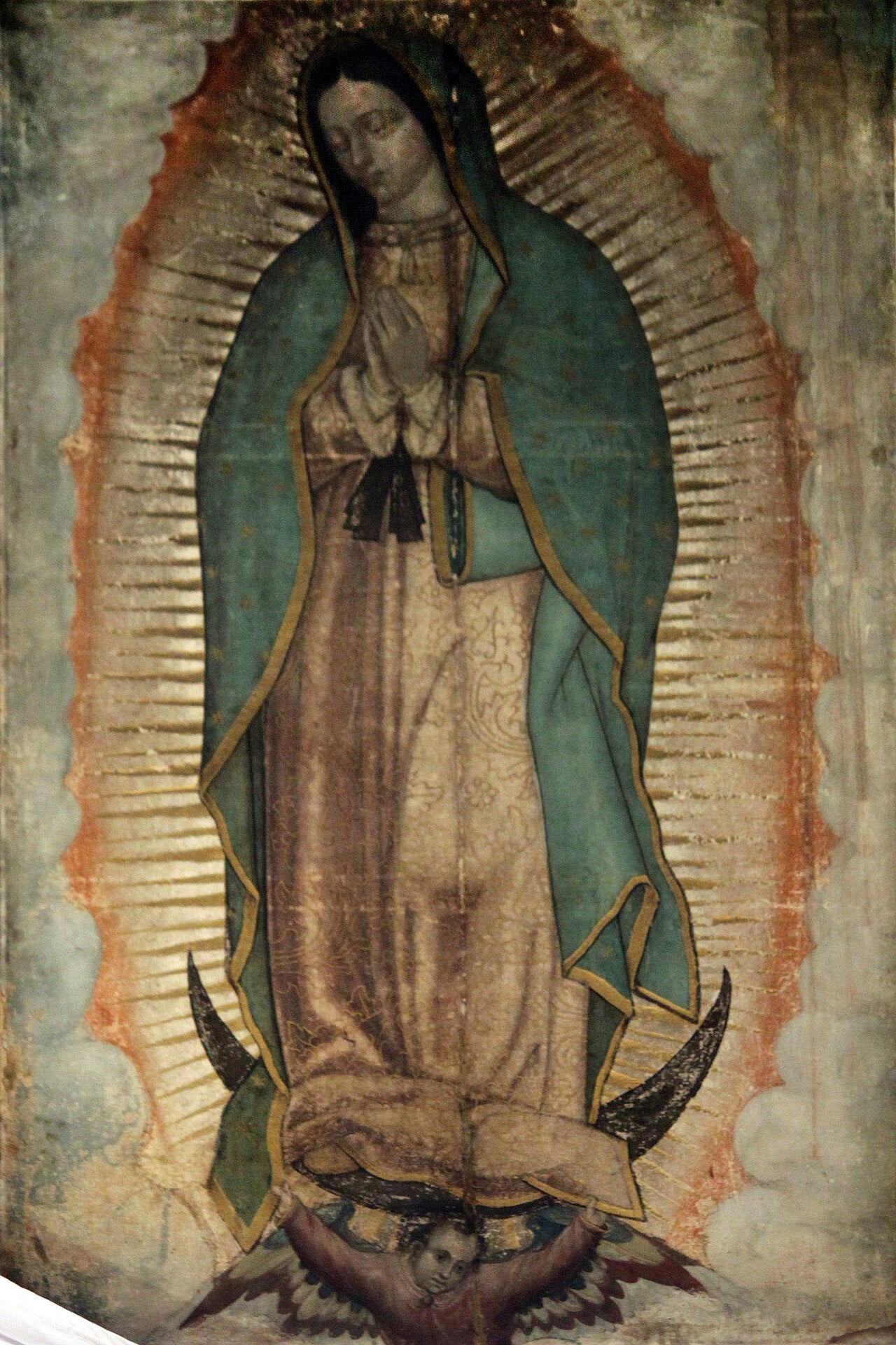 Pintura tradicional de Nuestra Señora de Guadalupe con manto estrellado, túnica rosada, rayos dorados alrededor y una media luna a sus pies sostenida por un ángel.