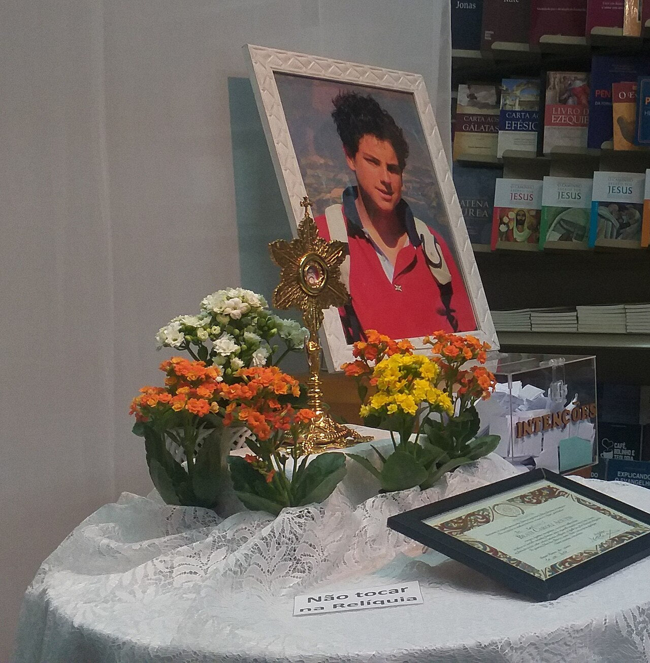 Retrato de Carlo Acutis junto a un relicario y flores durante una exposición en Río de Janeiro.