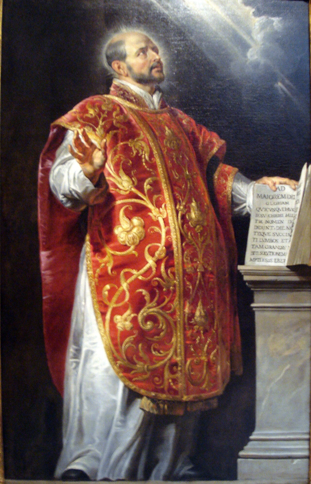 Pintura al óleo de San Ignacio de Loyola vistiendo casulla sacerdotal oscura y roja, mirando hacia arriba con expresión devocional.