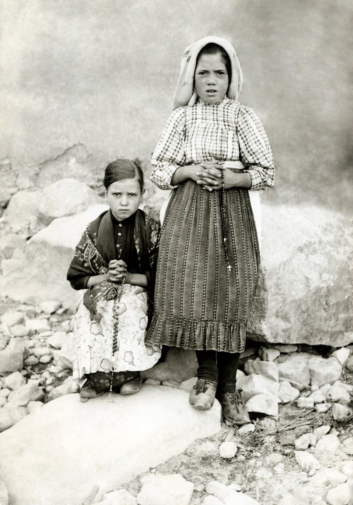 Fotografía histórica de Jacinta Marto sentada junto a su prima Lúcia Santos de pie.