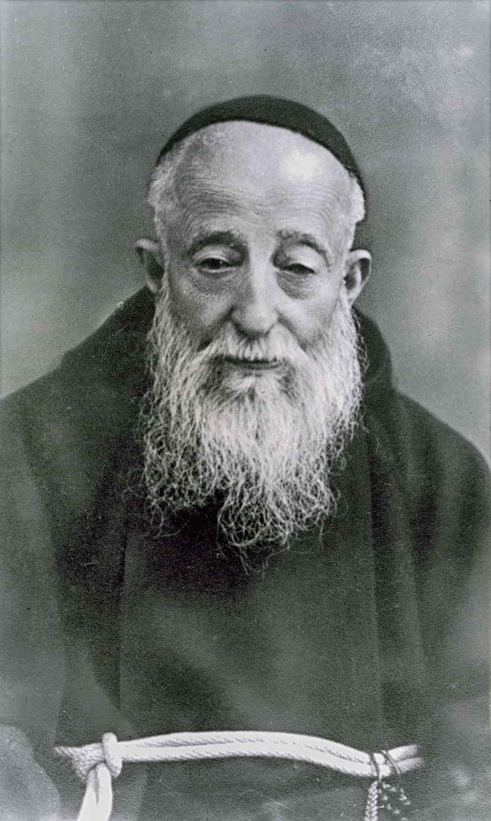 Retrato fotográfico de cuerpo entero de San Leopoldo Mandić con hábito capuchino y barba blanca.