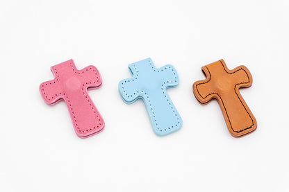 Tres marcapáginas magnéticos con forma de cruz en colores rosa, azul y marrón sobre fondo blanco.