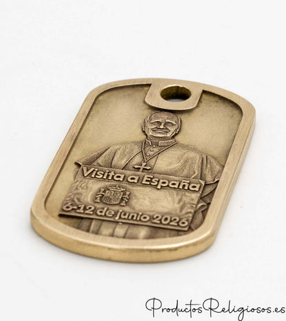Vista en perspectiva de un llavero conmemorativo metálico dorado con diseño tridimensional religioso.