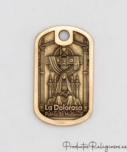 Primer plano del anverso del llavero de latón con iconografía religiosa detallada y texto grabado.