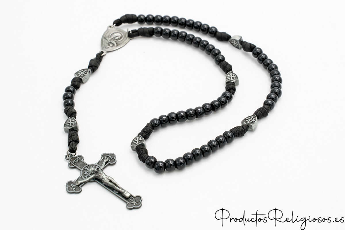 Rosario de cuentas negras brillantes con separadores metálicos troquelados y cruz de San Benito.